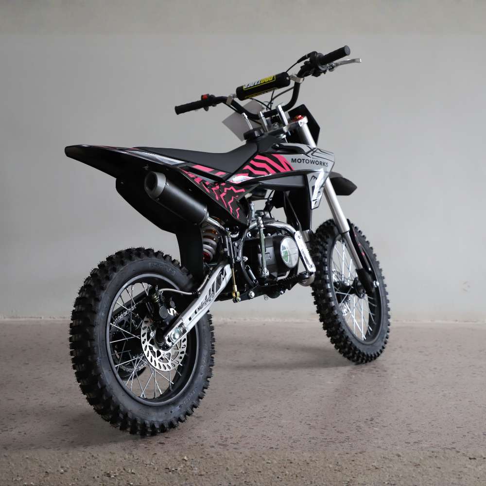 A black and silver dirt bike with pink and black zebra-like graphics on the side panels, photographed in a studio setting against a neutral gray background.