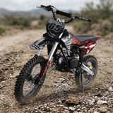 A youth dirt bike with a black, white, and red color scheme, standing on a rocky dirt trail in an outdoor desert setting.
