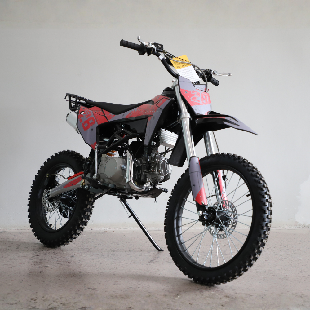 A mini dirt bike with a black and red body, silver engine, and knobby tires, shown on a kickstand in a studio setting.