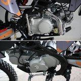 Close-up of a motorcycle engine and frame, showing the silver engine casing, black frame tubes, metal chain guard, and part of the bike's wheel and body panels.