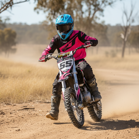 Person riding a dirt bike on a dirt track with trees in the background
