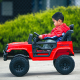 Side view of a young boy driving a red Jeep-inspired remote-controlled ride-on electric car outdoors, focused on the steering wheel