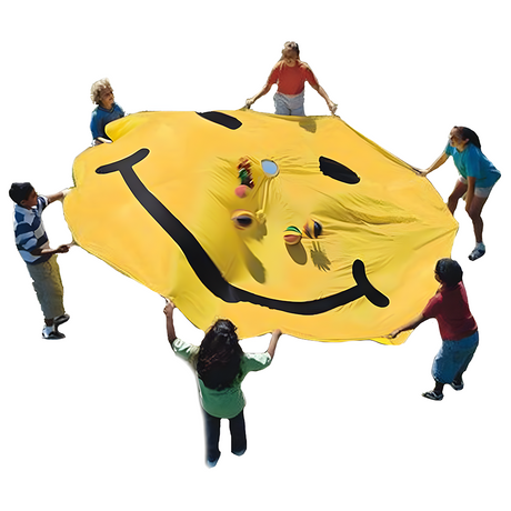 "Children holding up a yellow parachute with a black smiley face, while tossing colourful balls into the air