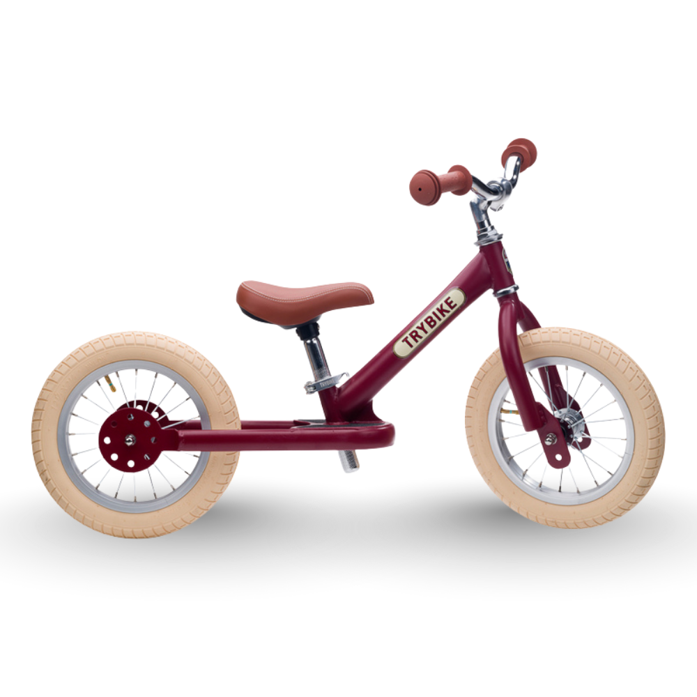Red balance bike with beige wheels on a white background