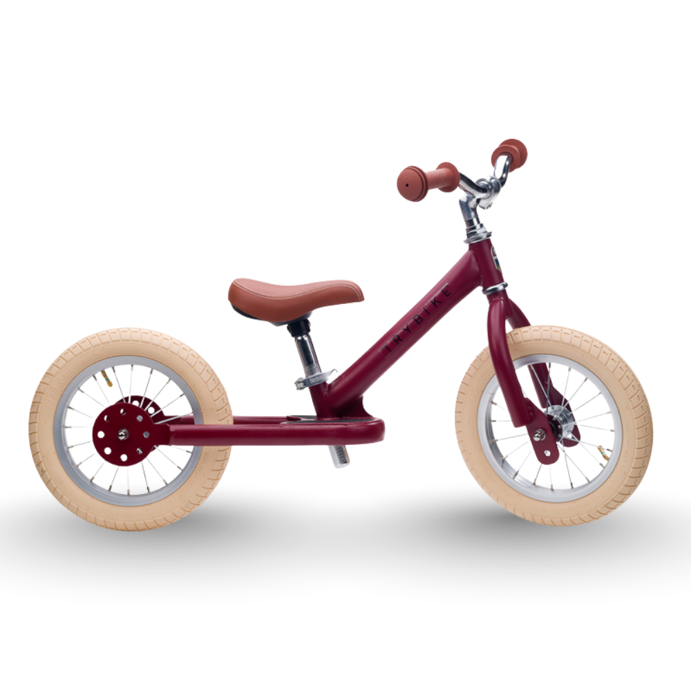 Red balance bike with beige wheels on a white background