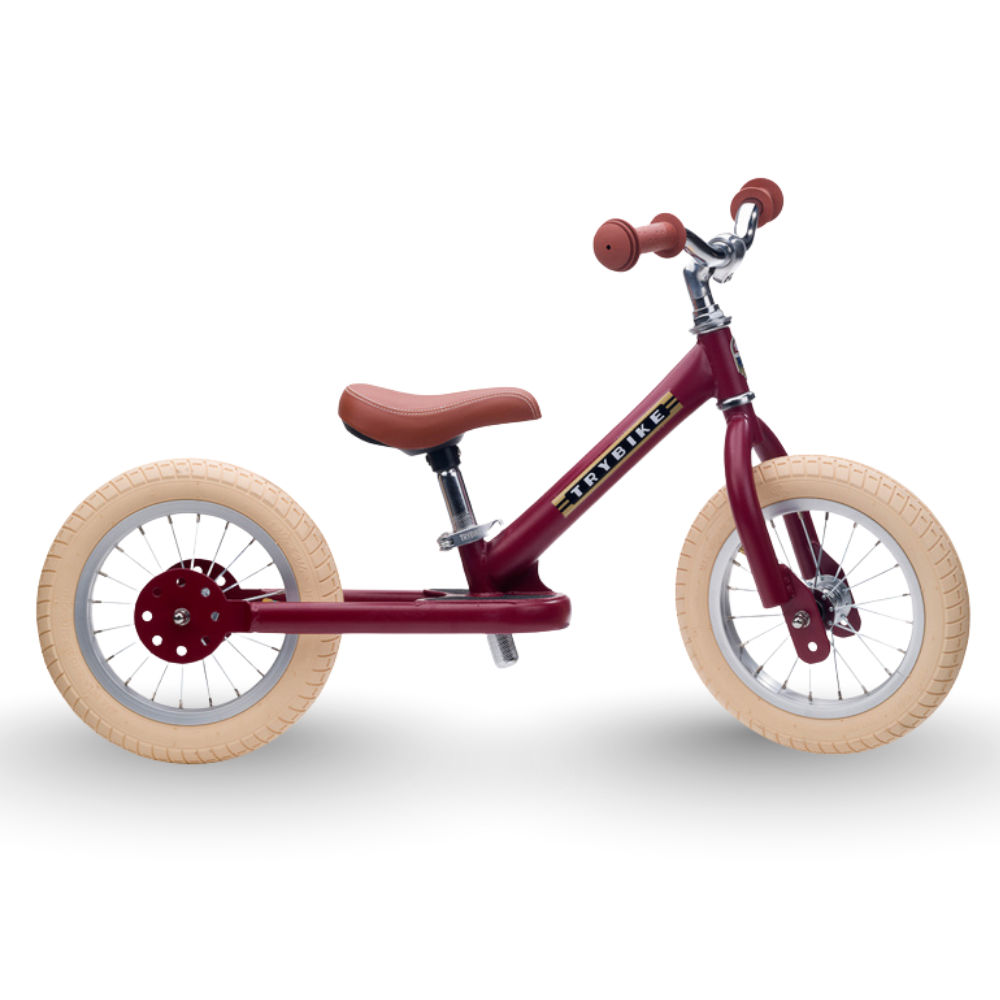 Red balance bike with beige wheels on a white background