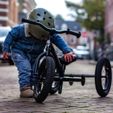 Child on a tricycle with a helmet in an urban setting
