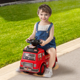 Child sitting on a red toy fire truck outdoors