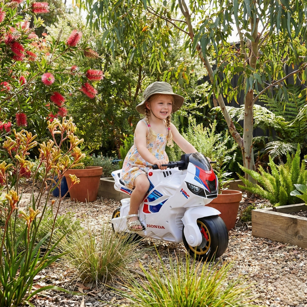 Child on a toy motorcycle in a garden setting
