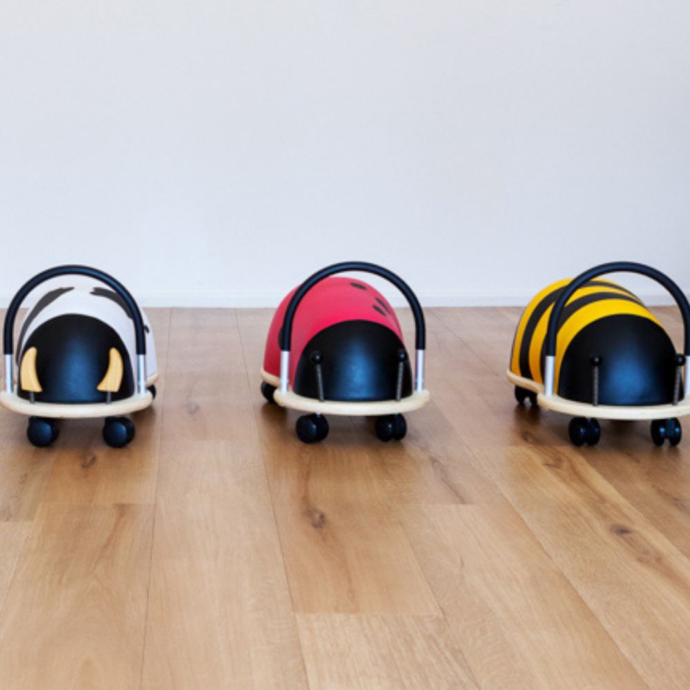 Three colorful baby buggies on a wooden floor with a white background
