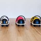 Three colorful baby buggies on a wooden floor with a white background