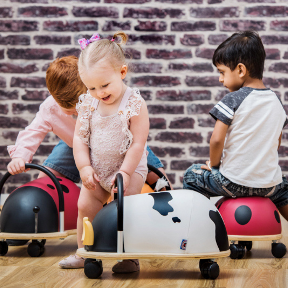 Children playing with animal-shaped toys against a brick wall.