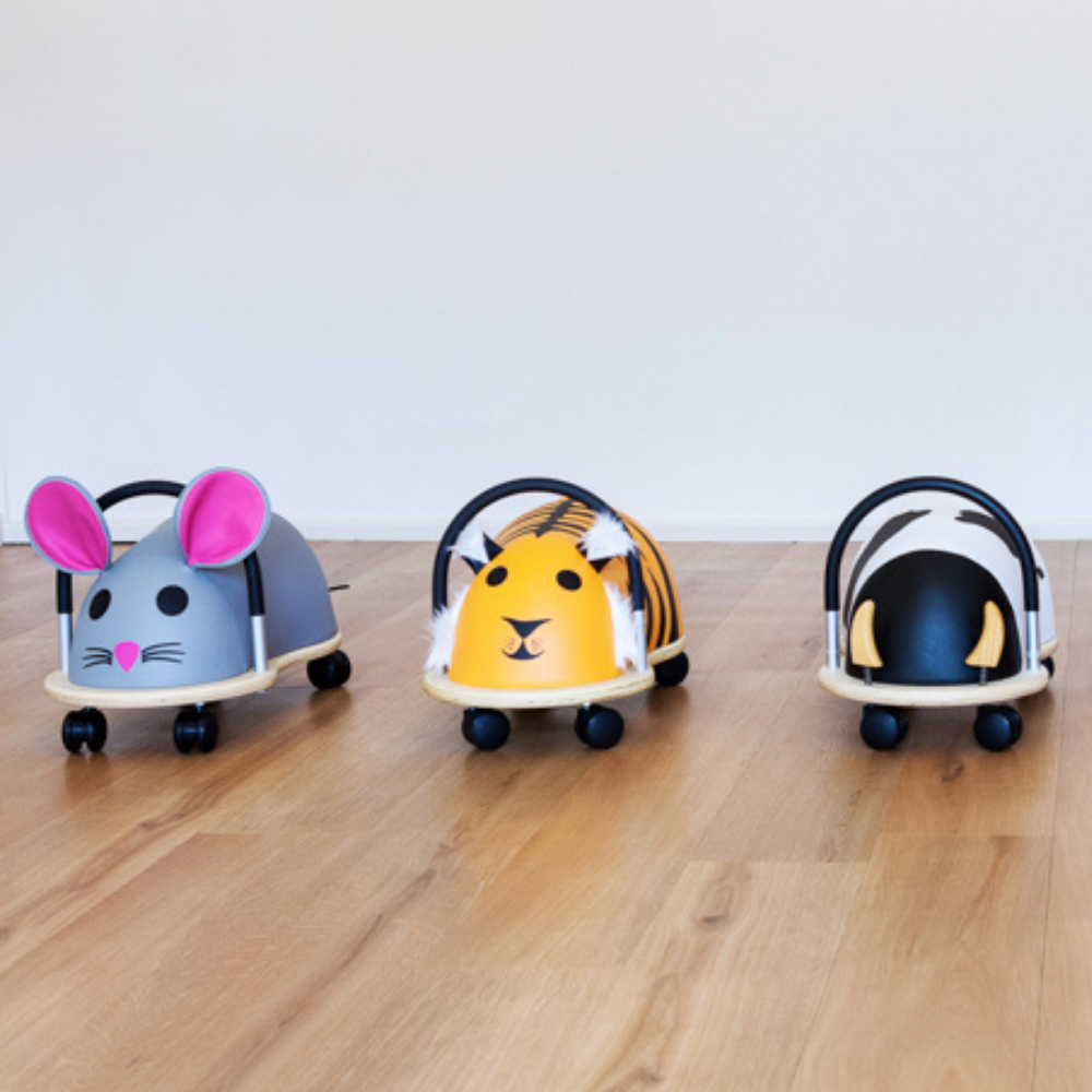 Three animal-themed baby buggies on a wooden floor with a white wall background