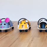 Three animal-themed toy cars on a wooden floor with a white background