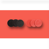 "Close-up image of black and red circular game tokens used for a giant Connect Four game, placed against a red background."
