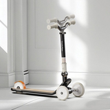 Children's scooter with white handlebars and wheels on a light gray floor.