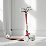 Red scooter with white wheels on a light gray floor