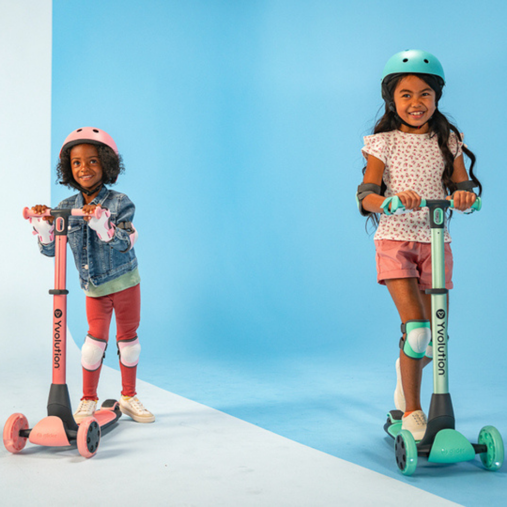 Two children on scooter with safety gear against a blue background