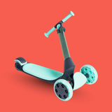 Children's scooter with light blue deck and white wheels on a red background