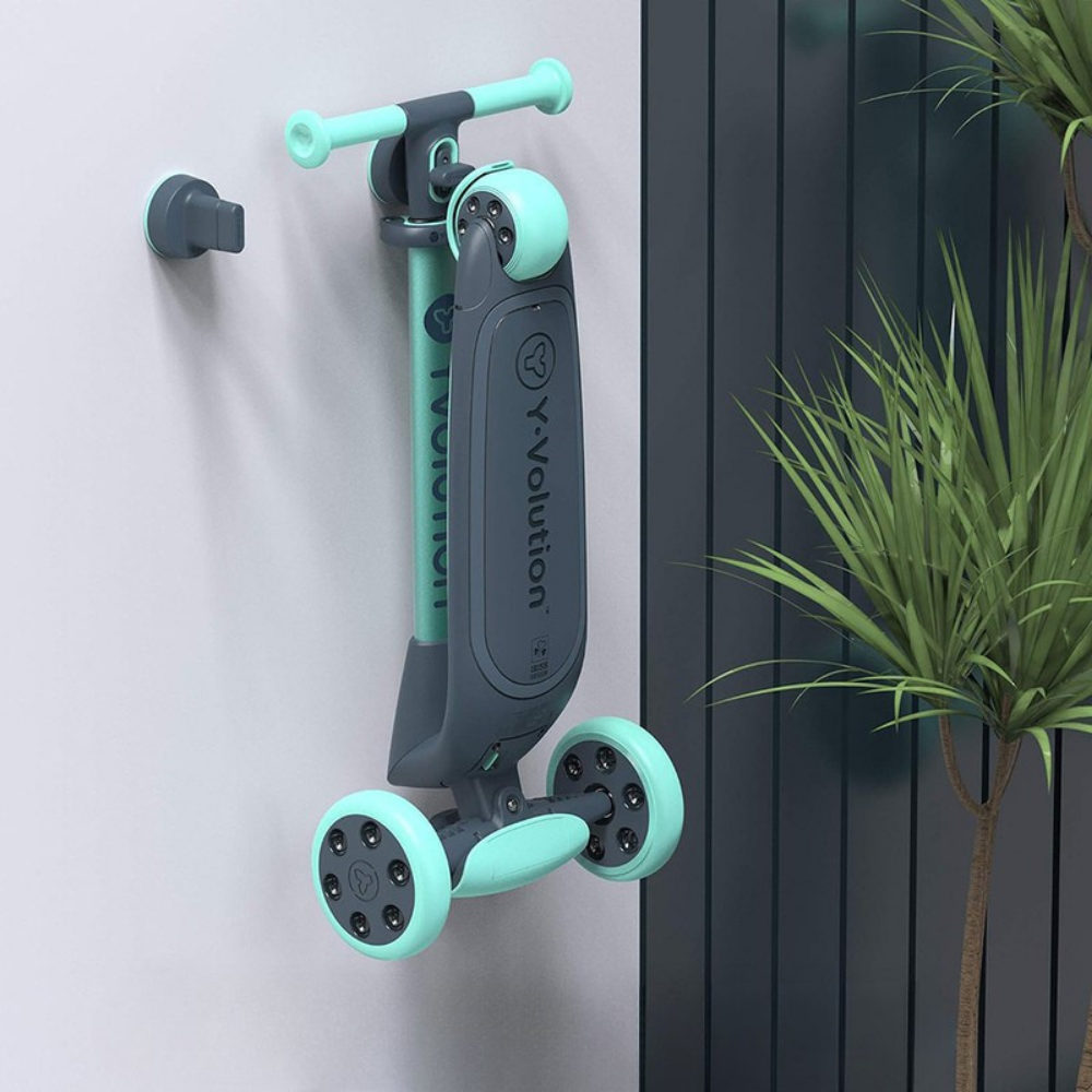 Green and black scooter attached to a wall with a plant in the background