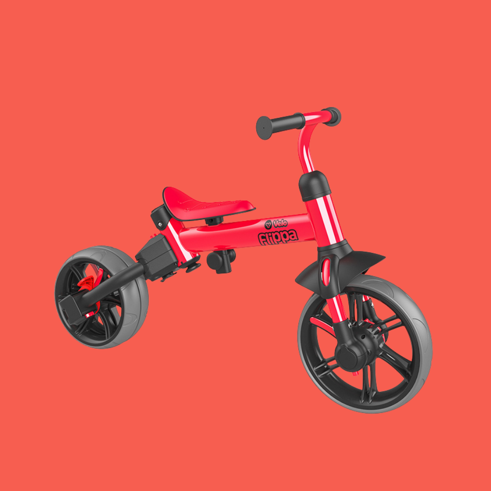 Red balance bike with black wheels on a red background