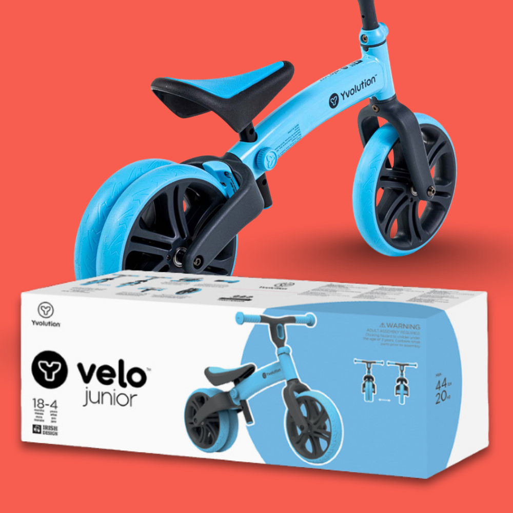 Blue balance bike with black wheels on a red background, next to its packaging box.