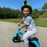 Child riding a blue balance bike outdoors on a sunny day