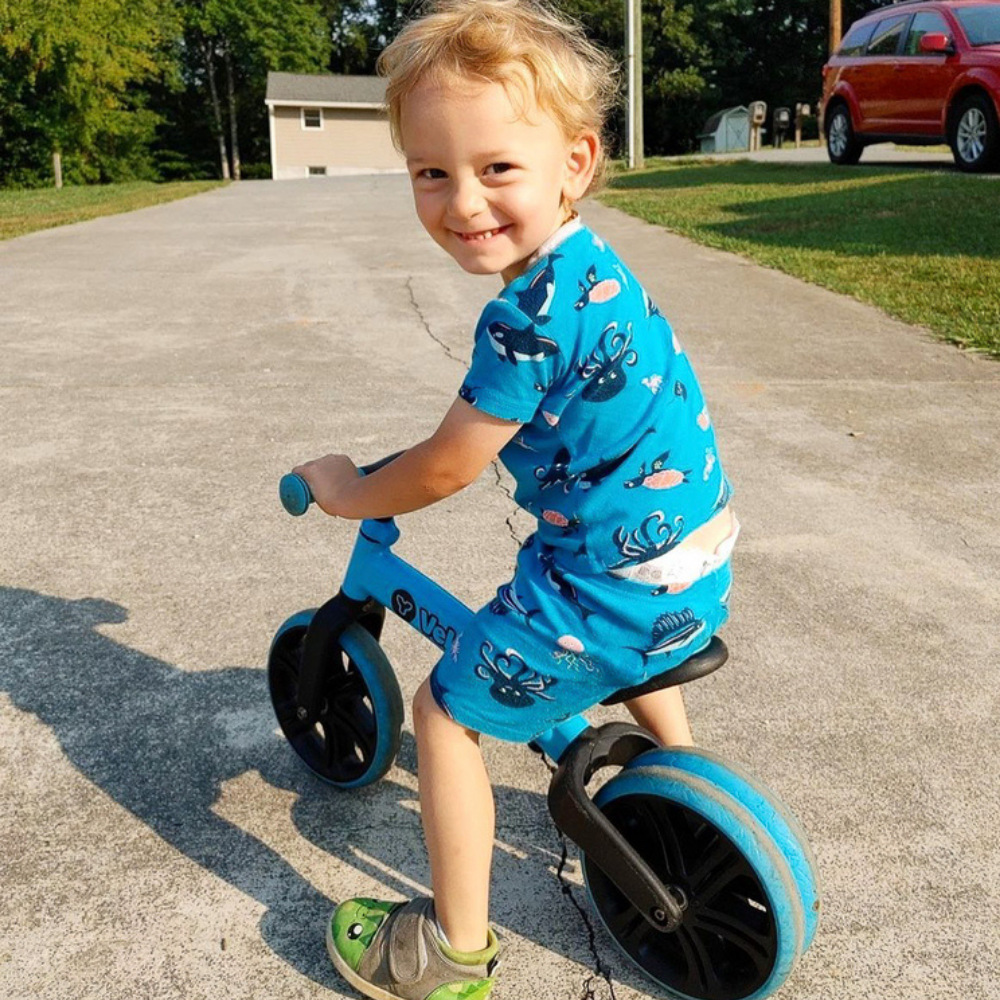 Child riding a blue balance bike on a driveway