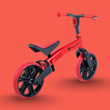 Red balance bike with black wheels on an orange background