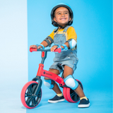 Child riding a red balance bike against a blue background