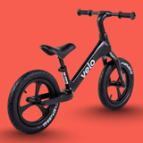 Black balance bike with 'velo' branding on an orange background