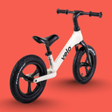 White balance bike with black tires and handlebars on a red background