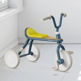 Children's tricycle with blue frame and yellow seat on a white floor.
