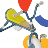 Children's balance bike with colorful abstract shapes in the background
