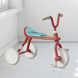 Red tricycle with a blue seat on a white floor