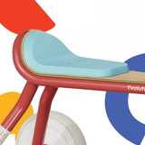 Children's balance bike with colorful geometric shapes in the background